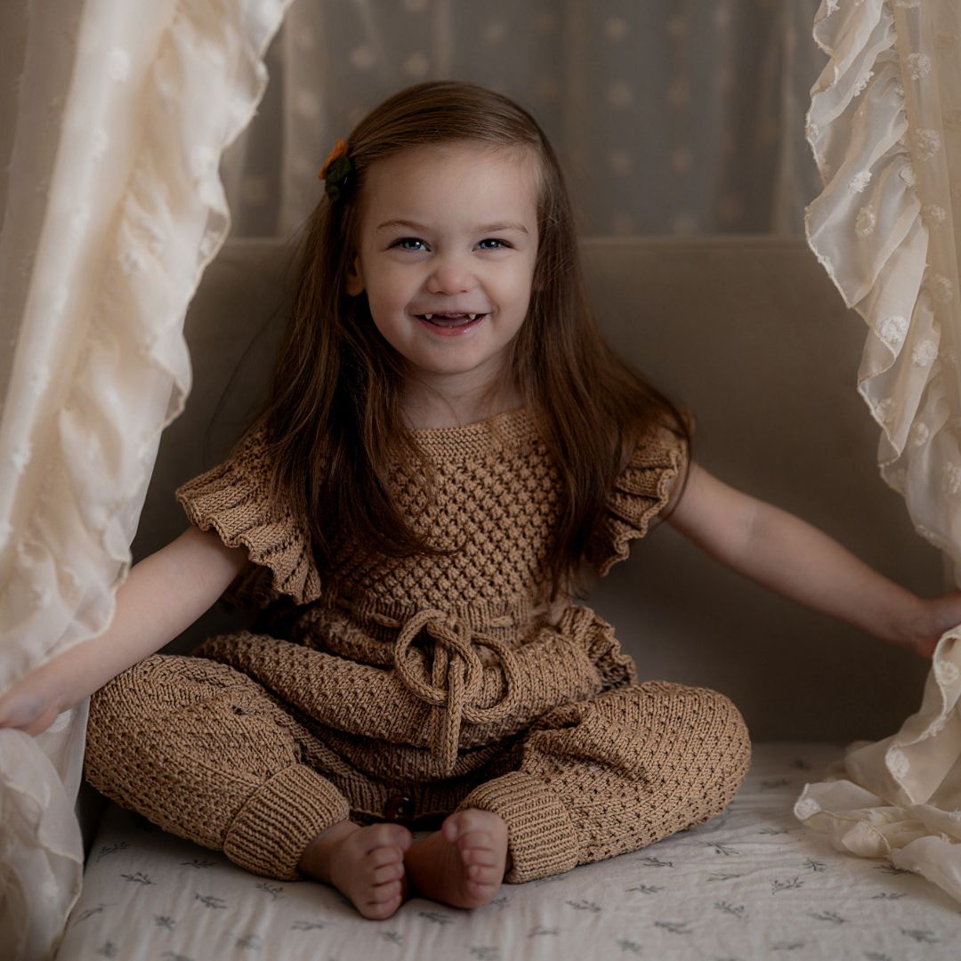 Hand knitted romper with ruffle sleeves, drawstring waist and ruffles