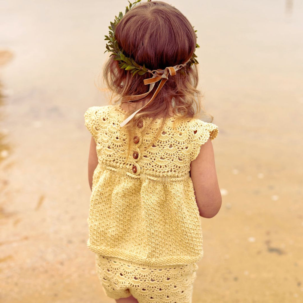 Baby wearing the Lucy Tunic Top and Bloomers Set by JuneBee Baby, a hand knitted cotton and bamboo outfit in yellow