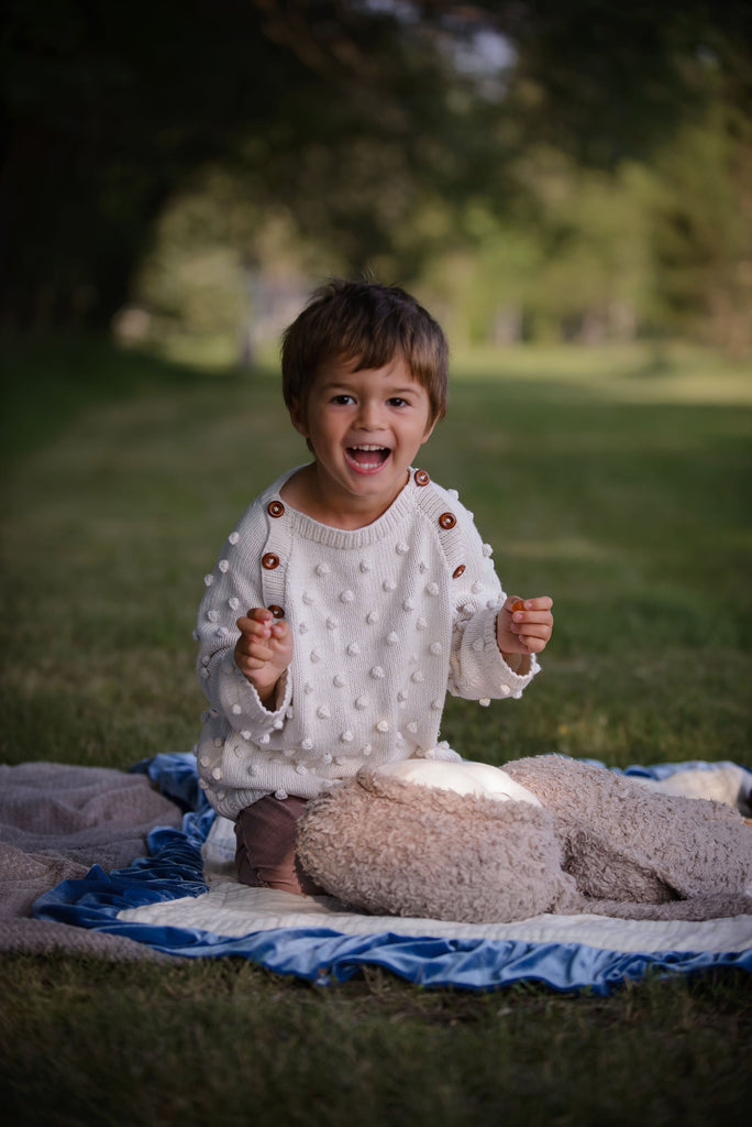 Toddler wearing a handmade popcorn knit cotton sweater by JuneBee Baby, a versatile natural fiber piece for a minimalist children's wardrobe