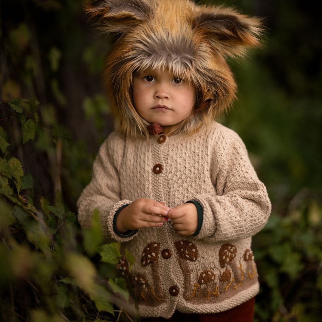 Toddler wearing a hand-knit mushroom cardigan in light oatmeal cotton bamboo.