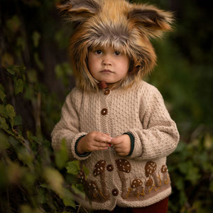 Toddler wearing a hand-knit mushroom cardigan in light oatmeal cotton bamboo.
