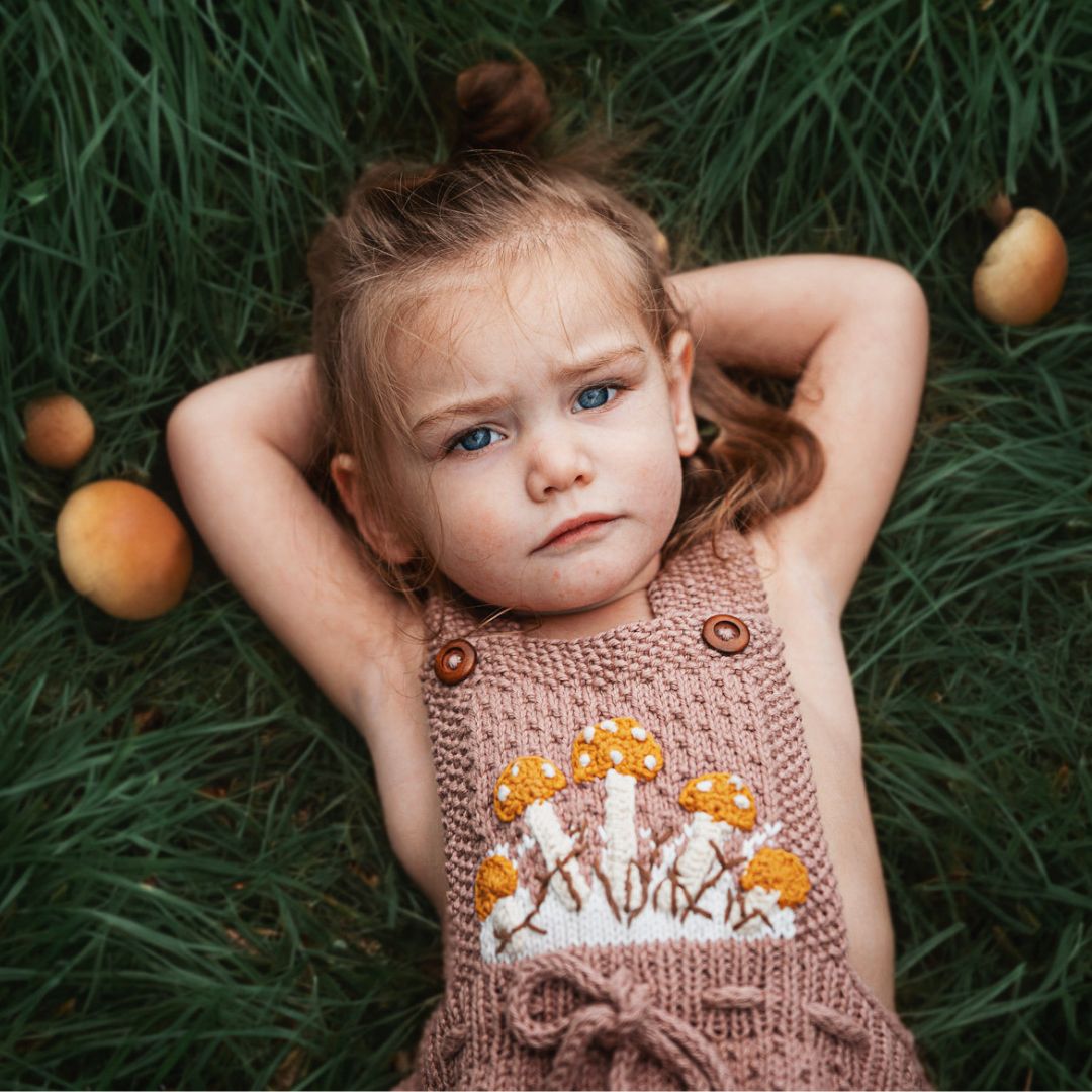 Toddler girl in artisan-made mushroom romper in cotton bamboo, eco-friendly slow fashion toddler outfit.