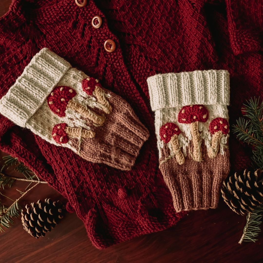 Flat lay of hand-knit mushroom leg warmers in creamy green cotton bamboo, mushroom baby stuff for kids by JuneBee Baby.