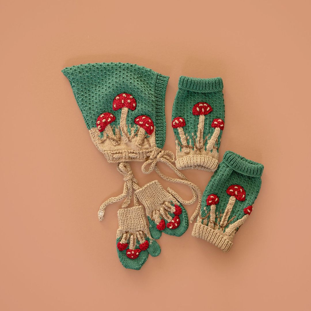 Picture of hand-knit accessories set in hunter green cotton bamboo, featuring pixie hat, leg warmers and mittens with hand-crocheted mushrooms.