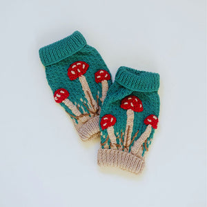 Flat lay of hand-knit mushroom leg warmers in hunter green cotton bamboo, artisan-made kids mushroom accessories.