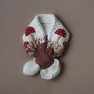 Flat lay of hand-knit mushroom neck scarf in creamy light green cotton bamboo, kids mushroom accessories by JuneBee Baby.