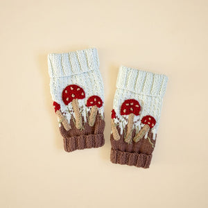 Close-up flat lay of hand-knit mushroom leg warmers in creamy green cotton bamboo showing mushroom motif detail.