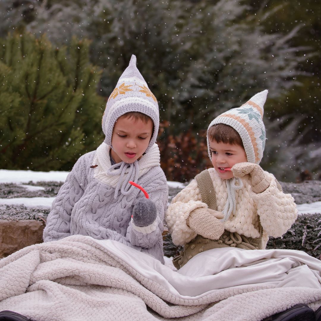 Kids wearing unisex Nordic pixie hats in hand-knit cotton bamboo with snowflake motifs.